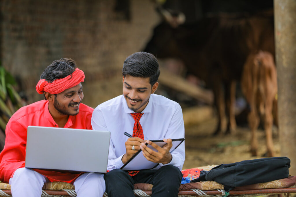 Young indian banker collection information to farmer at home